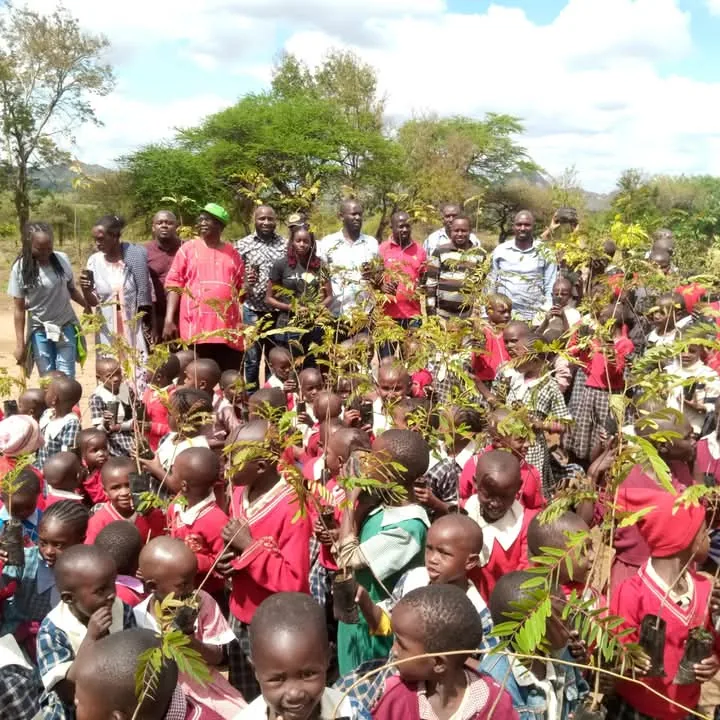 Pupils and community members planting tree seedlings at Vota Primary School